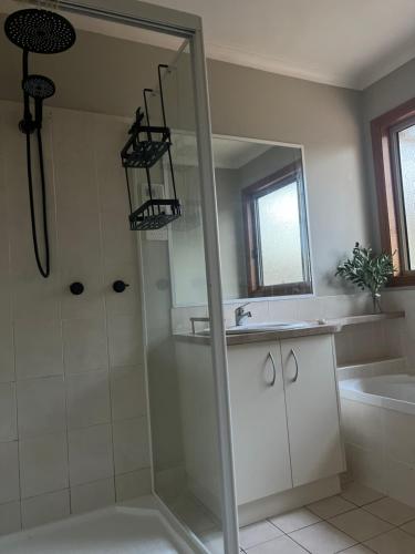 a bathroom with a shower and a sink and a mirror at Greenwood Cottages in Tolmie