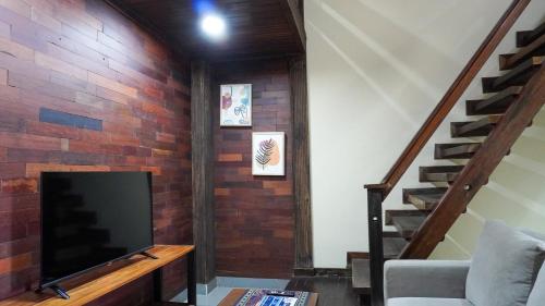 a living room with a tv and a brick wall at Alu Lofts in Seminyak