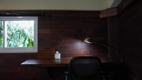 a desk with a lamp and a chair next to a window at Alu Lofts in Seminyak