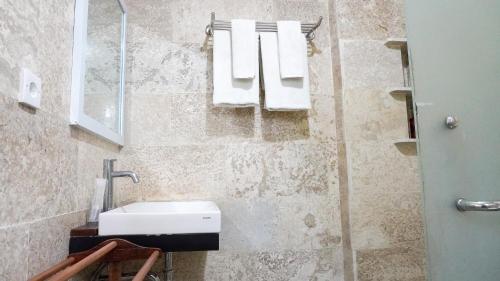 a bathroom with a sink and towels on a wall at Alu Lofts in Seminyak