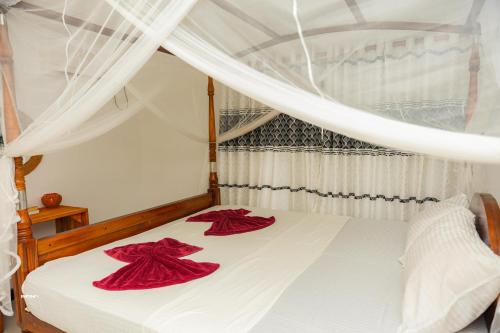 a bedroom with a white bed with red sheets and curtains at Hanguk Villa Mirissa in Mirissa