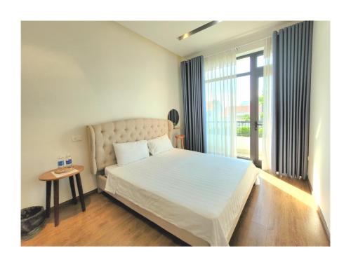 une chambre avec un lit blanc et une fenêtre dans l'établissement Sunshine villa, à Ấp Long Hồ Hạ
