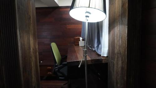 a room with a desk with a lamp and a green chair at Alu Lofts in Seminyak