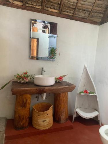 a bathroom with a sink and a mirror and a chair at Les Lodges de La Buvette ÉCO LODGE RESTAURANT in Ile aux Nattes