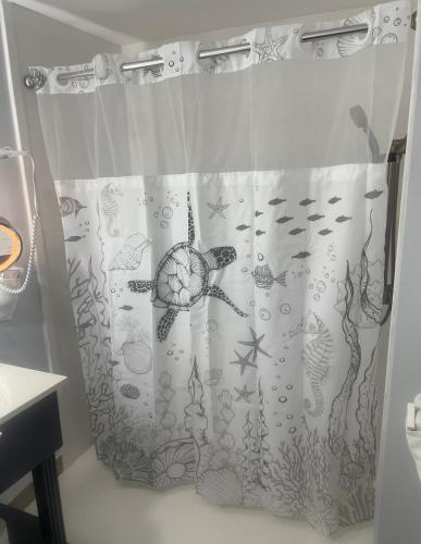 a shower curtain with a fish design on it at Ocean Sands Beach Boutique Inn-1 Acre Private Beach-St Augustine Historic-2 Miles-Shuttle with Downtown Tour-HEATED Salt Water Pool until 420AM-Popcorn-Cookies-New 4k USD Black Beds- 69 Item Breakfast-Eggs-Bacon-Starbucks- Free Laundry- #904-799-SAND in Saint Augustine
