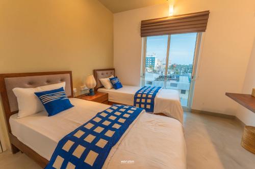 a bedroom with two beds and a window with a view at 50 By The Sea in Dehiwala