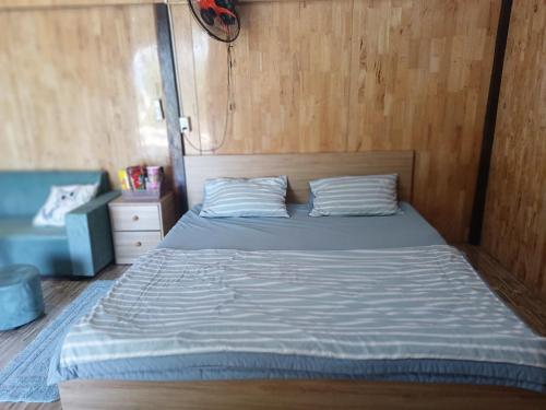 a bed in a room with a wooden wall at The Sunrise Anh Tu in Cam Ranh