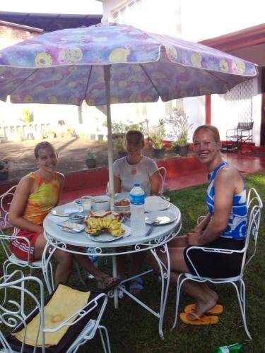 three people sitting at a table under an umbrella at No 06 Veediya Bandara Lane Bahirawakanda in Kandy