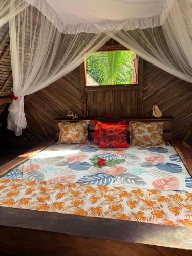 a large bed in a room with a window at Les Lodges de La Buvette ÉCO LODGE RESTAURANT in Ile aux Nattes
