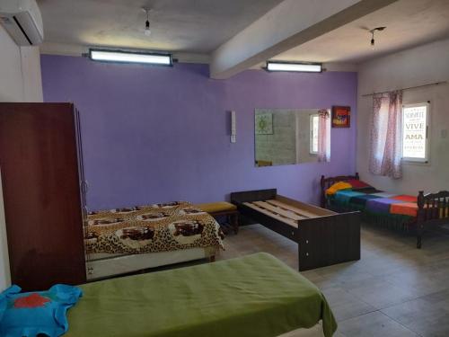Habitación con 2 camas y paredes moradas. en Rinconcito Don Antonio, en Tinogasta