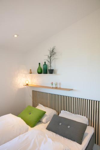 a bed with two green pillows on top of it at Strandhuset. in Asperup