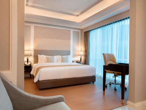a hotel room with a bed and a desk and a desk at Wyndham Panbil Batam in Batam Center