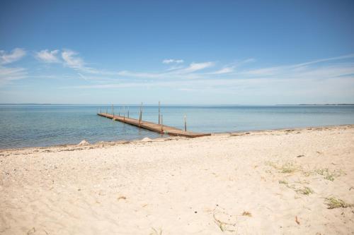 a dock in the water next to a beach at Strandhuset. in Asperup