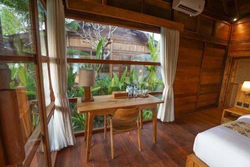a bedroom with a desk in a room with a window at Ubud Art Resort in Ubud