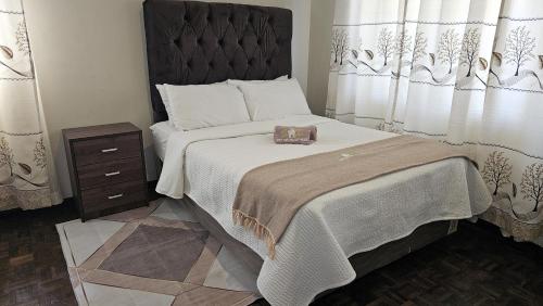 a bedroom with a large bed with a wooden headboard at Palm West in Bulawayo