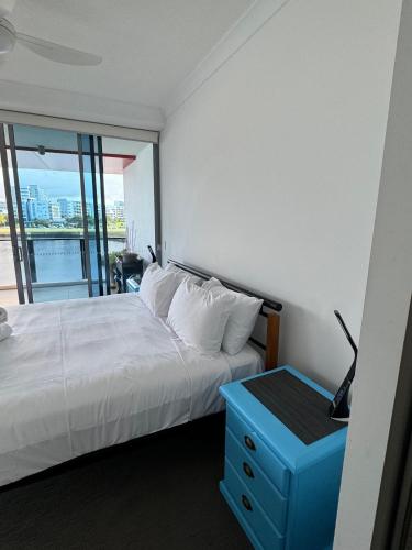 a bedroom with a white bed and a blue night stand at Harbour Quays Apartments in Gold Coast