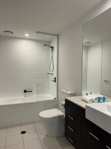 a bathroom with a tub and a toilet and a sink at Harbour Quays Apartments in Gold Coast