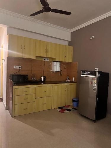 a kitchen with wooden cabinets and a black refrigerator at Luxury Apt near Palolem Beach, WFH with Forest view in Canacona