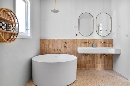 une salle de bain avec un lavabo blanc et deux miroirs dans l'établissement Pacific Paradise - 4 Bedroom House Central Coast, à Long Jetty