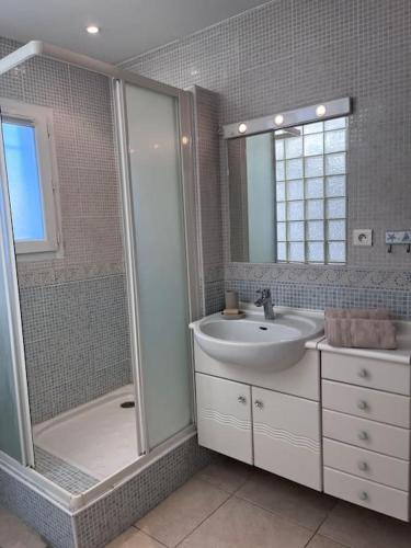 une salle de bain avec un lavabo et une douche dans l'établissement La maison de la plage pied dans l eau, à La Ciotat