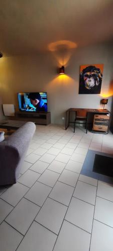 un salon avec un canapé et une télévision à écran plat dans l'établissement Maison de ville, à Kergrist