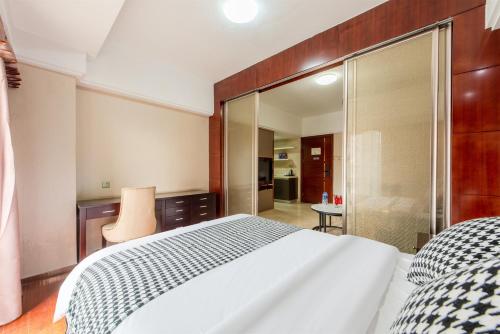 a bedroom with a large white bed and a glass wall at 寓洣公寓佛山铂顿祖庙岭南天地店 in Foshan