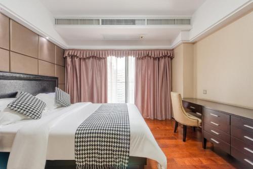 a bedroom with a bed and a desk and a window at 寓洣公寓佛山铂顿祖庙岭南天地店 in Foshan