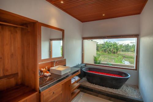 ein Bad mit einer schwarzen Badewanne und einem Fenster in der Unterkunft Alam selasih villa in Gianyar