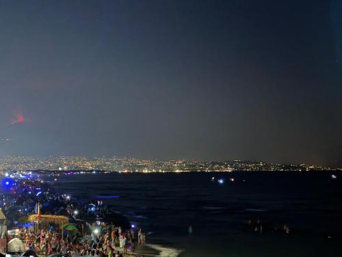 a crowd of people standing on the beach at night at Paradiso fronte Mare in Agnone Bagni