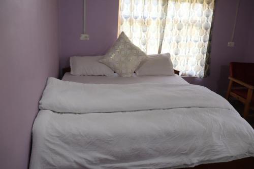 a bedroom with a bed with white sheets and a window at Hotel Tserap View in Padam