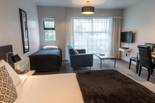 a room with a bed and a living room with a couch at 315 Euro Motel and Serviced Apartments in Dunedin