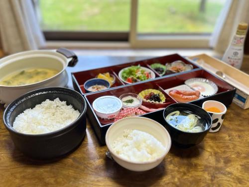 een tafel met kommen eten en rijst bij Nature Cottage Akabeko in Kitashiobara