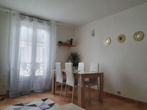 une salle à manger avec une table et des chaises blanches dans l'établissement Joli deux pièces au 14ème arrondissement à Paris, à Paris