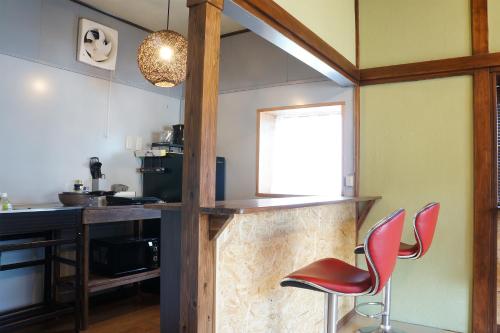 a kitchen with two red chairs and a counter at IG3 宇佐美駅近海近の完全貸切ビーチハウス お宿三感四温 Oyado Sankanshion in Ito
