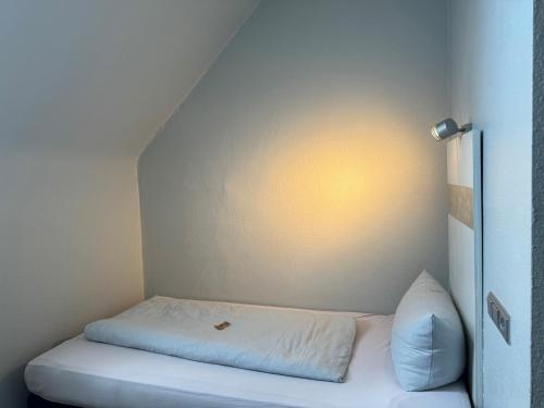 a small bed in a small room with a white wall at Badischer Hof in Bühl