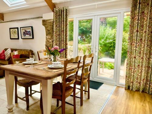 a dining room with a table and chairs and a window at Hideaway Cottages - Greenacres Estates in Tenby