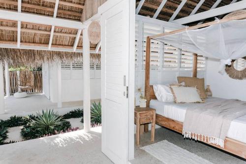 a bedroom with a canopy bed in a white room at Rote White House - South Villa & Loft in Nembrala