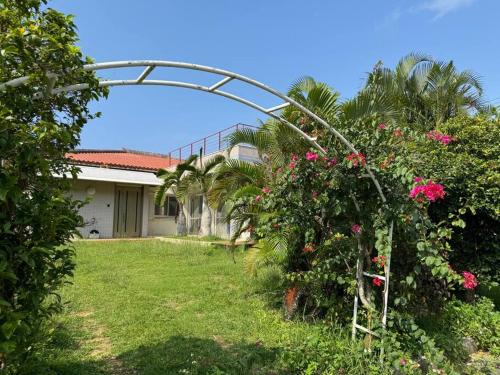 a garden with a arch with pink flowers and a house at 海王屋 Kaioya in Fukai