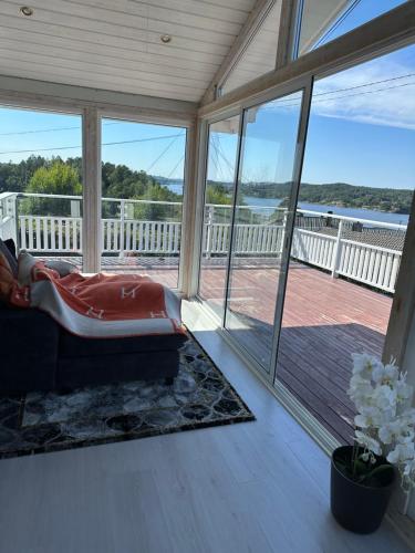 a screened in porch with a couch and a large window at Flott sørlandshus ved sjøen leies ut in Arendal