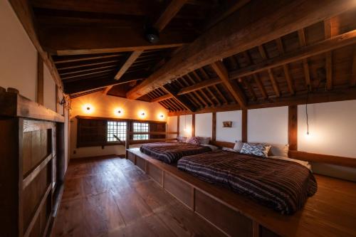 two beds in a large room with wooden ceilings at 源泉かけ流しの一棟貸し温泉宿The Bath & Bed Dogo in Matsuyama