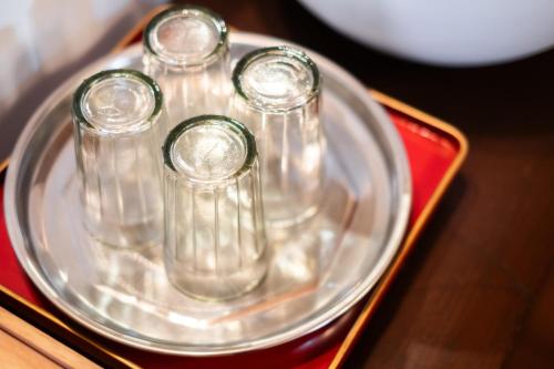 a silver tray with four glass bottles on a table at 源泉かけ流しの一棟貸し温泉宿The Bath & Bed Dogo in Matsuyama
