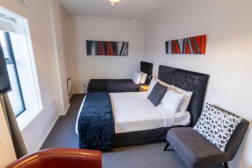 a bedroom with a bed and a chair and a tv at 315 Euro Motel and Serviced Apartments in Dunedin