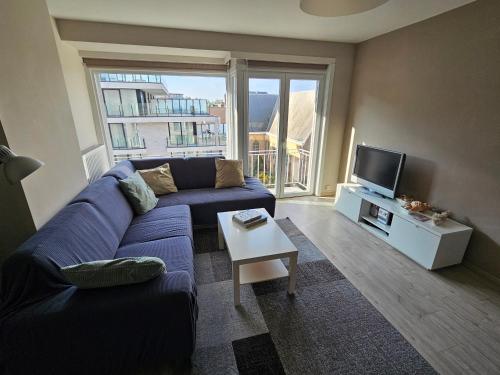 un soggiorno con un divano blu e una TV di Côte à l'Oostduinkerke met gratis garage a Oostduinkerke