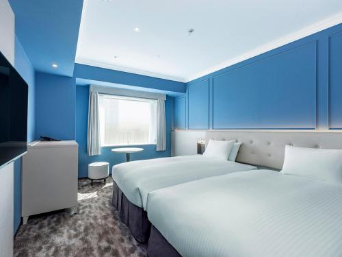 a blue room with two beds and a window at Oriental Hotel Tokyo Bay in Urayasu