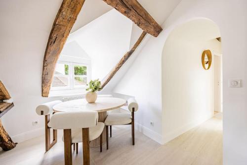 une salle à manger blanche avec une table et des chaises en bois dans l'établissement 3 bedrooms Sacrée cœur Place du Tertre Montmartre, à Paris