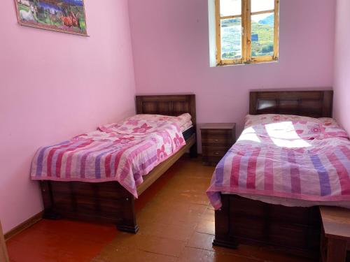 two beds in a room with pink walls at Villa QALDEA in Ushguli
