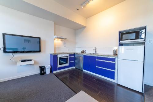 a kitchen with blue cabinets and a flat screen tv at 315 Euro Motel and Serviced Apartments in Dunedin