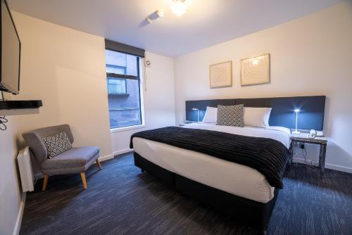 a bedroom with a large bed and a chair at 315 Euro Motel and Serviced Apartments in Dunedin