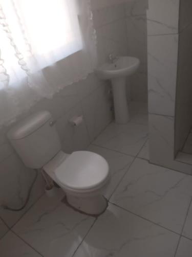 a white bathroom with a toilet and a sink at Arcon Guest House in Vanderbijlpark