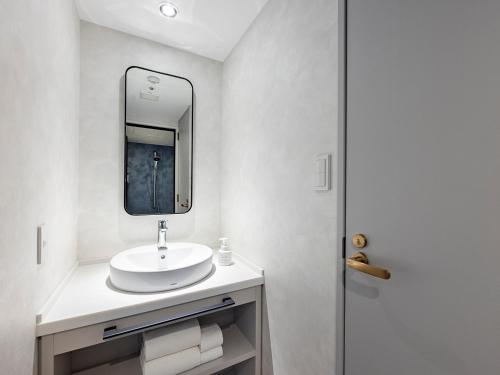 a white bathroom with a sink and a mirror at Oriental Hotel Tokyo Bay in Urayasu